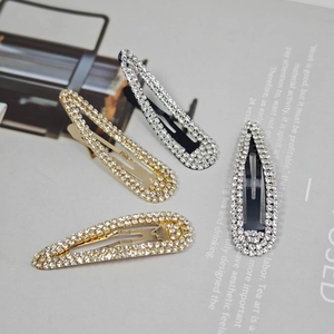 Close-up of four teardrop hair clips with shimmering rhinestones in gold and black finishes