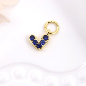 Golden heart-shaped pendant set with six deep blue zircons on a white textured background