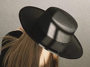Artistic shadow play on the texture of a classic black wide-brimmed wool felt boater hat