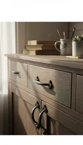 Close-up of vintage black cast iron handle on a rustic wooden cabinet with distressed finish