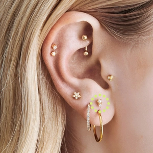Close-up of gold stud earrings with pearls and crystals on ear lobe for women