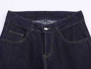 Détails du jean bleu foncé montrant la taille, la braguette à boutons et les surpiqûres