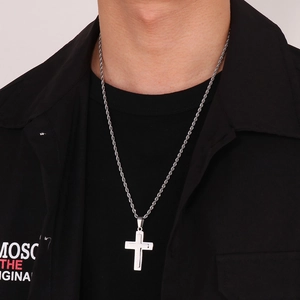 Detail shot of a double-layered silver cross necklace worn with a twisted rope chain
