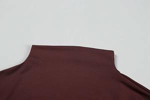 Detailed close-up of dark reddish-brown high-neck knit dress with refined stitching