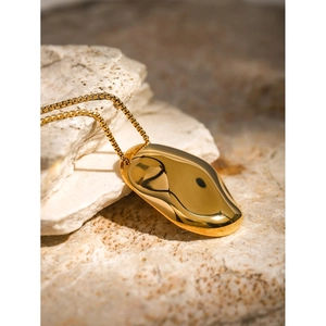 Detailed view of an 18k gold plated irregular hammered pendant on a minimalist chain