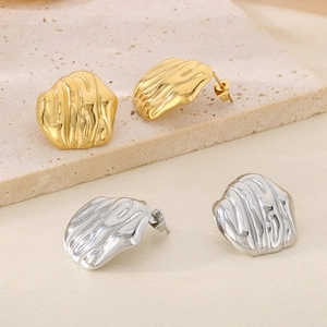 Macro detail of irregular pleated texture earrings in gold and silver finish