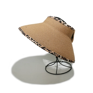 Detail of beige straw sun visor with leopard print edge on a round display stand