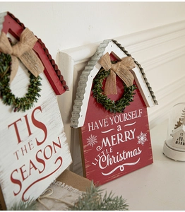 Close-up of wooden Christmas house ornaments with corrugated metal roofs and linen bows