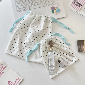 Close-up of two white polka dot drawstring storage bags with SORAKKA brand label