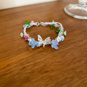 Detailed close-up of a resin butterfly and flower bead necklace on a wooden surface