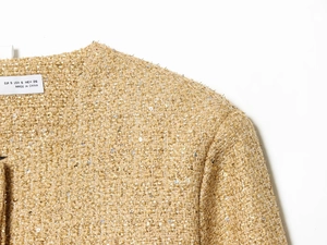 Dettaglio della giacca in tweed oro champagne con paillettes e cuciture del collo