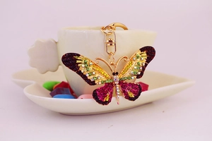 Detail of a gold butterfly keychain featuring colorful pink, yellow and green rhinestones