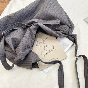 Detailed view of dark grey pleated canvas fabric texture on a large capacity shoulder bag