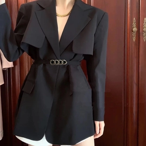 Detail of a black tailored blazer featuring a stylish gold chain waist belt and layered lapel