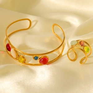 Detail of bohemian gold bracelet and ring set with colorful natural stones on silk