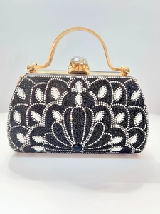Close-up of black beadwork handbag with gold metal handle and crystal buckle detail