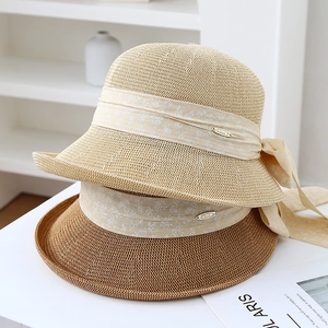 Detail of straw sun hats with floral ribbon bows and metal plates in a clean setting