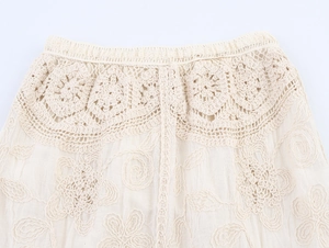 Detalle de la cintura bohemia de ganchillo con bordado floral en falda de playa crema