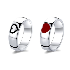 Detailed view of silver couple rings with red enamel heart and black hollow heart design