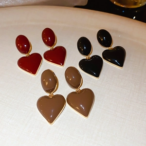 Close-up of vintage heart drop earrings in red, black, and brown with gold trim edges