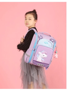 Girl wearing a purple school backpack with 3D unicorn wings on a pink studio background