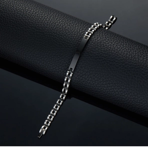 Close-up of black and silver stainless steel chain bracelet on black leather texture