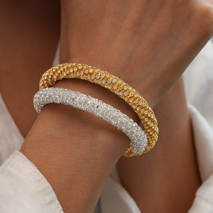 Gros plan de bracelets en or et argent avec strass sur le poignet d'une femme chic