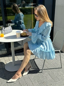 Close-up of sky blue V-neck chiffon dress with ruffle details and flared sleeves in sunlight