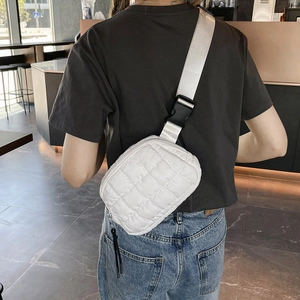 White quilted waist bag with adjustable wide strap and black tassel shown on a model's back