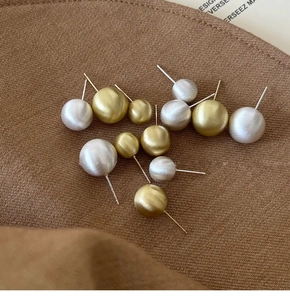 Macro shot of assorted gold and silver brushed metal stud earrings on textured fabric