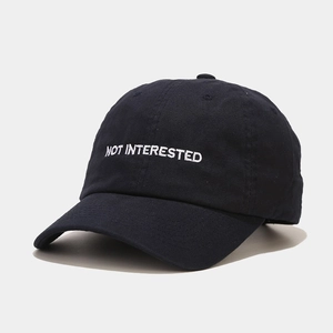 Detail of NOT INTERESTED embroidery on a navy cotton twill baseball cap fabric
