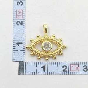 Macro view of gold-plated evil eye pendant with zircon and measuring scale for size