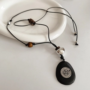 Détail du collier bohème avec perles en bois et croix en cristal sur pendentif noir