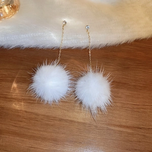 Detailed close-up of fluffy white mink fur ball earrings with sparkling zircon studs