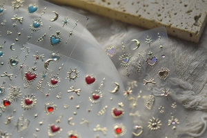 Macro shot of gold foil nail art stickers with butterfly and heart crystal designs