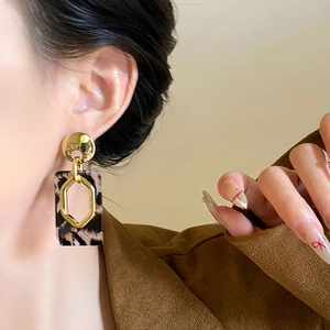 Close-up of geometric earrings with leopard resin and golden hexagon details