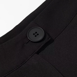 Dettaglio ravvicinato di un bottone nero a quattro fori e cuciture su pantaloni eleganti
