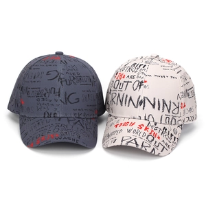 Detail of grey and white baseball caps with graffiti print and curved brim texture