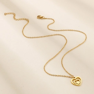 Elegant gold double heart necklace with hollow design on beige background