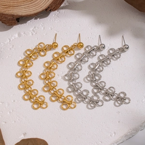 Boucles d'oreilles trèfle minimalistes en or et argent sur fond de pierre
