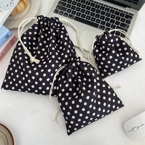 Three-piece black drawstring organizer set with white polka dots for travel storage