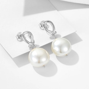 Minimalist 925 sterling silver knot earrings with large white pearls on a white card