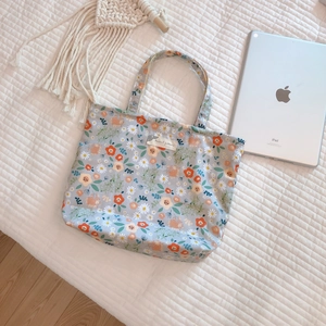 Light blue floral canvas tote bag with orange flower patterns and textile label