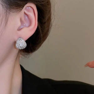 Macro view of crystal teardrop stud earrings worn by a model in elegant suit