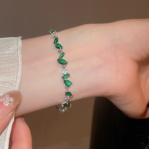 Macro d'un bracelet fleuri en zircons verts au poignet avec détail en dentelle
