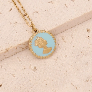 Macro shot of gold circular pendant with blue enamel and relief silhouette detail