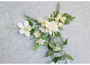 Detailed top view of realistic white floral hair clips with green fern leaves on felt