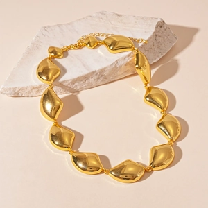 Dettaglio macro della collana a maglie geometriche dorate su espositore in pietra