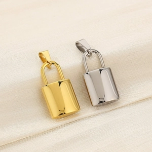 Polished gold and silver padlock charms on beige silk background showing metallic texture