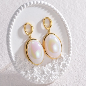 Elegant gold earrings with iridescent oval stones on floral relief stand